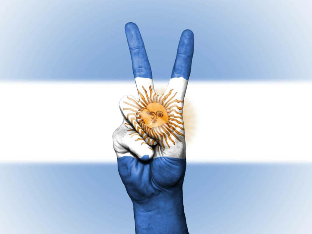 Hand painted Argentina flag on hand showing peace sign with national colors background wallpaper