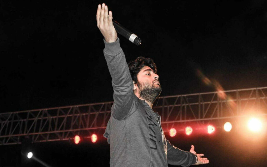 Arijit Singh energetic live concert performance singing passionately under vibrant stage lights Wallpaper