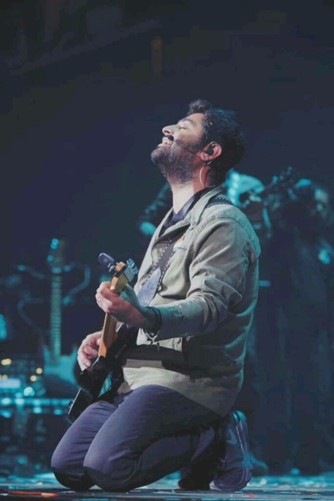 Arijit Singh passionately playing guitar on stage immersed in energetic live music performance Wallpaper