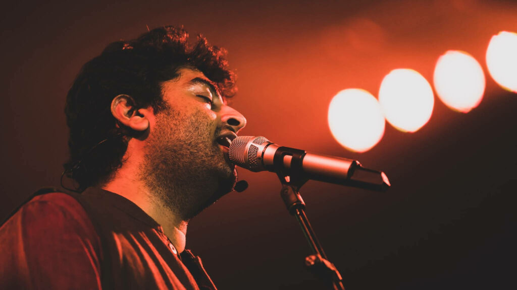 Indian singer Arijit Singh performing live on stage in Chicago 2015 with warm stage lighting Wallpaper