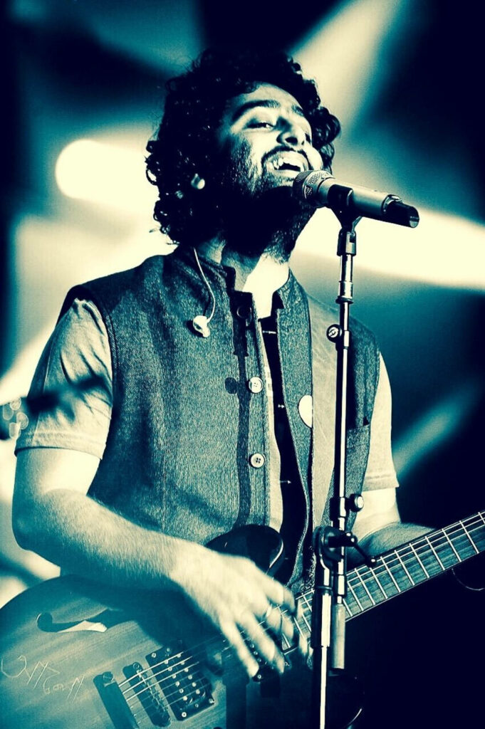 Arijit Singh live performance singing and playing guitar under dramatic stage lights wallpaper