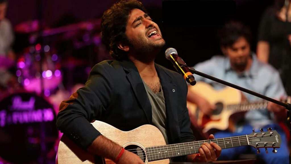 Arijit Singh singing and playing guitar passionately on stage creating electrifying concert vibe Wallpaper