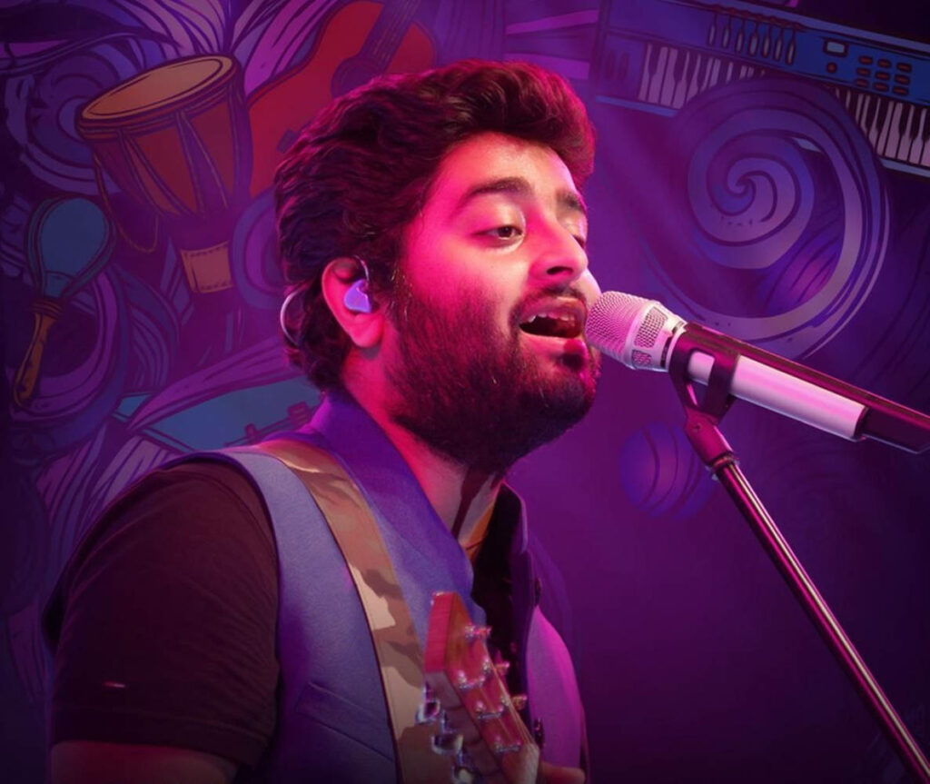 Indian singer Arijit Singh performing live on stage with vibrant lighting and musical backdrop Wallpaper