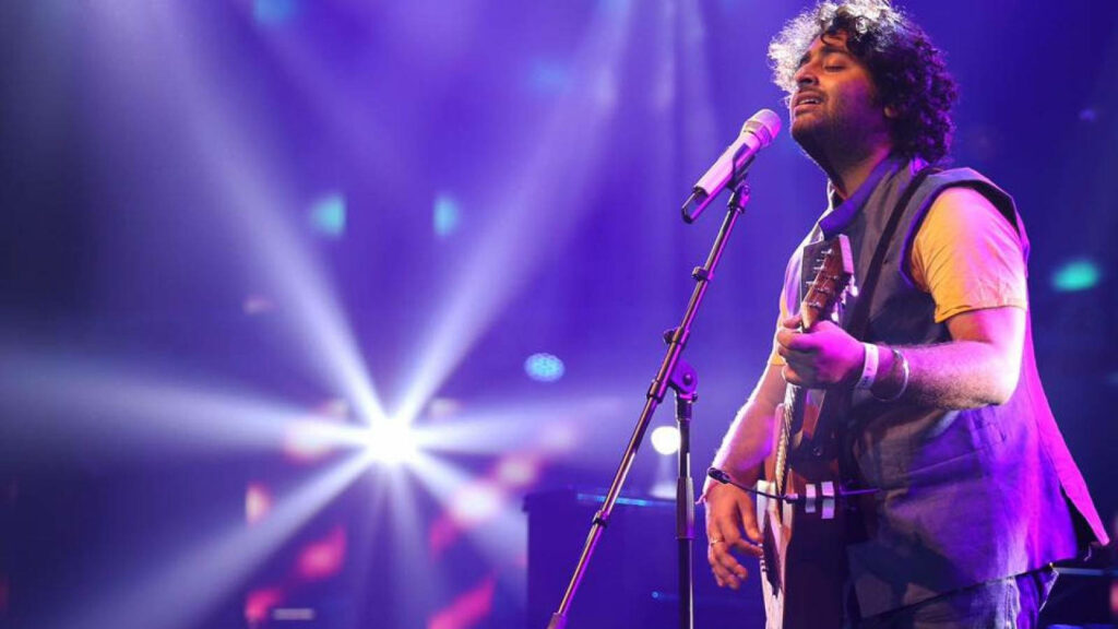 Arijit Singh singing passionately on stage with vibrant purple lighting and captivating music vibe Wallpaper