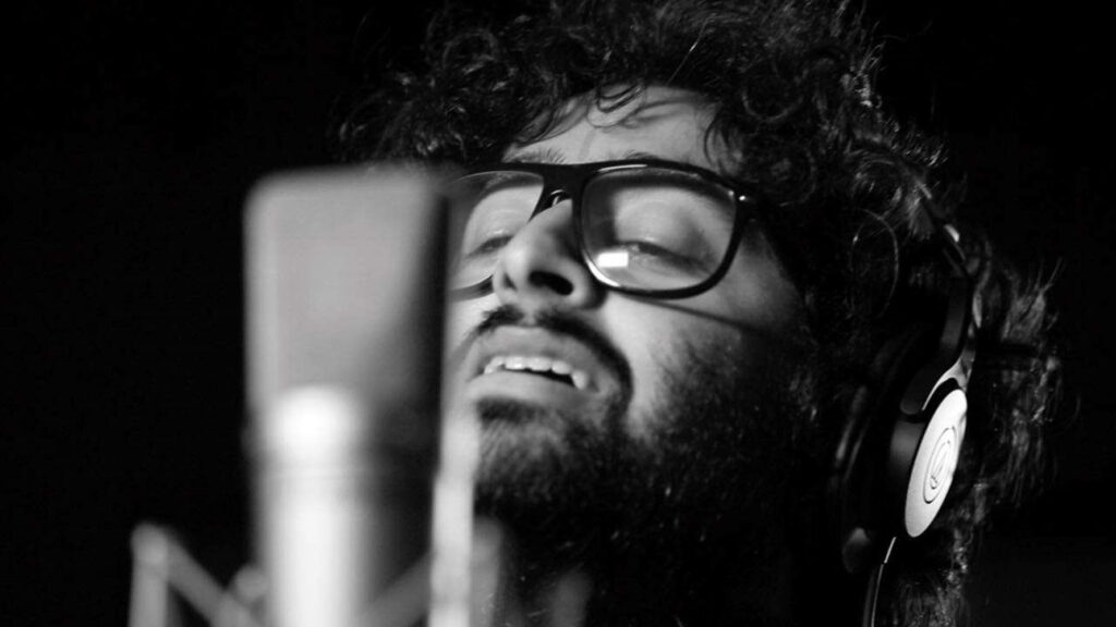 Arijit Singh singing passionately in recording studio with headphones and microphone closeup Wallpaper