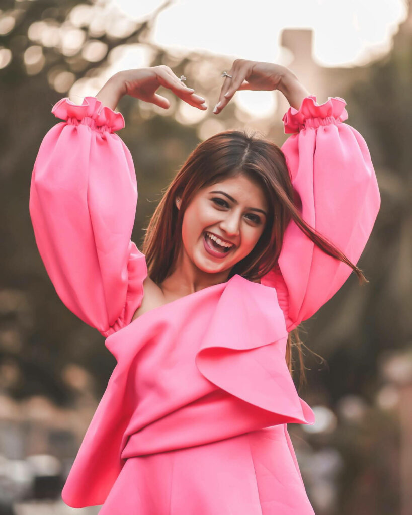 Arishfa Khan joyful in bright pink outfit posing outdoors vibrant colorful wallpaper background