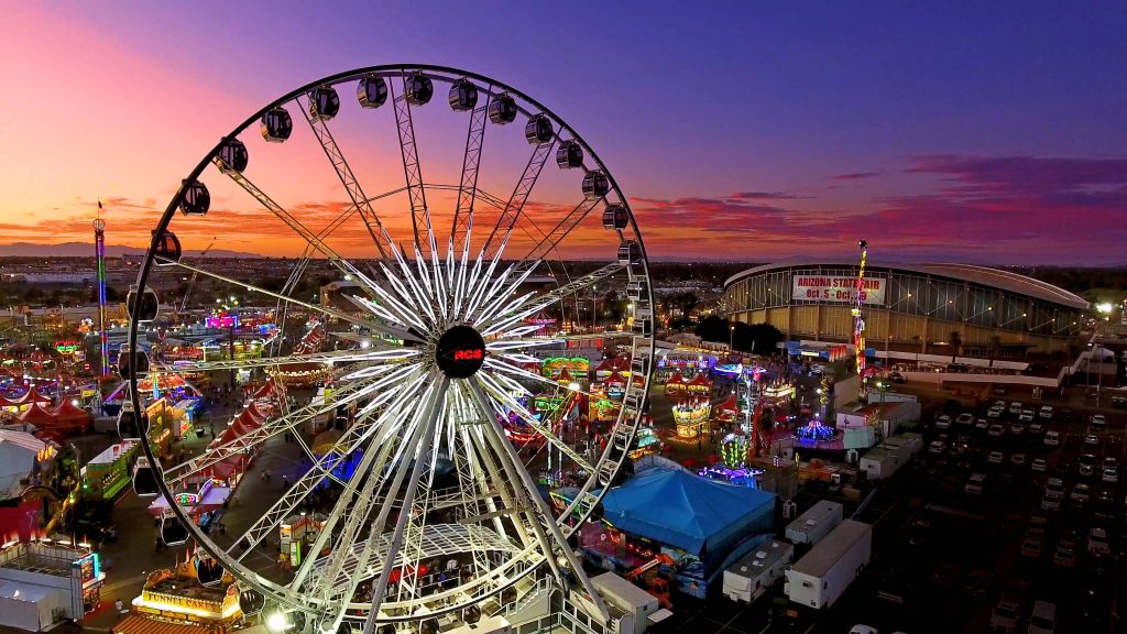 Birds-eye view of Arizona State Fair Ferris wheel glowing at sunset over vibrant fairgrounds wallpaper