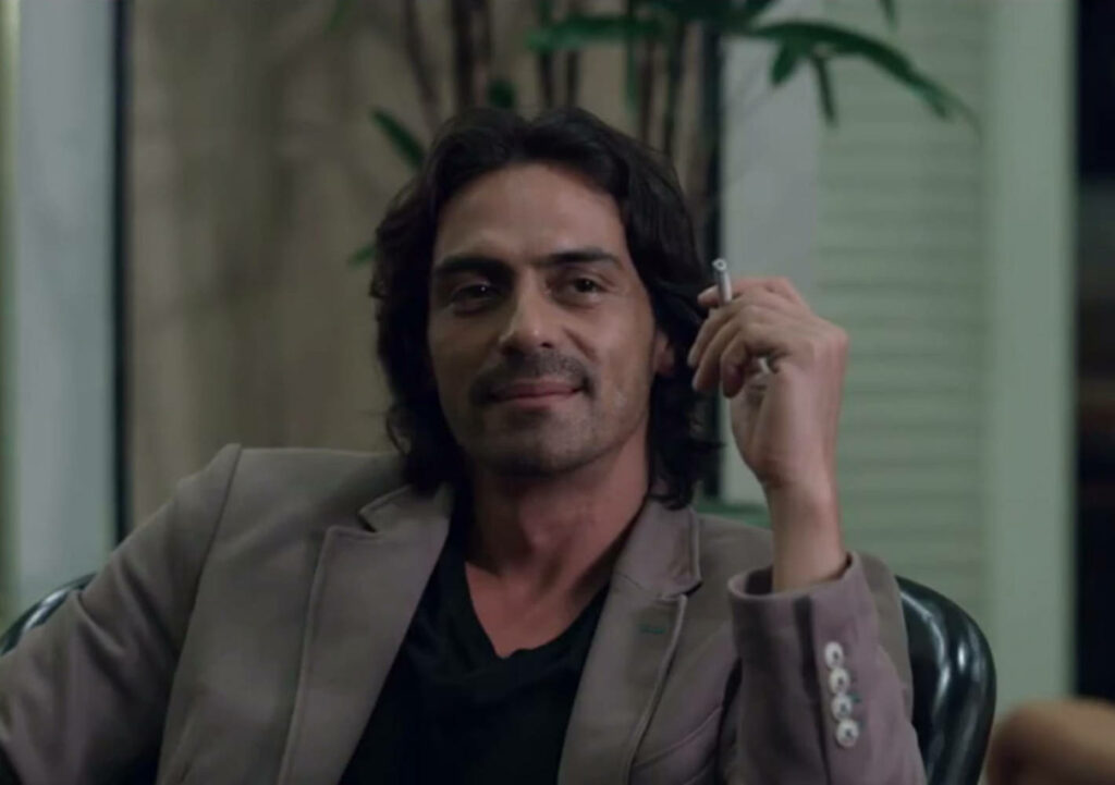 Arjun Rampal sits confidently holding cigarette stick in stylish wallpaper background setting