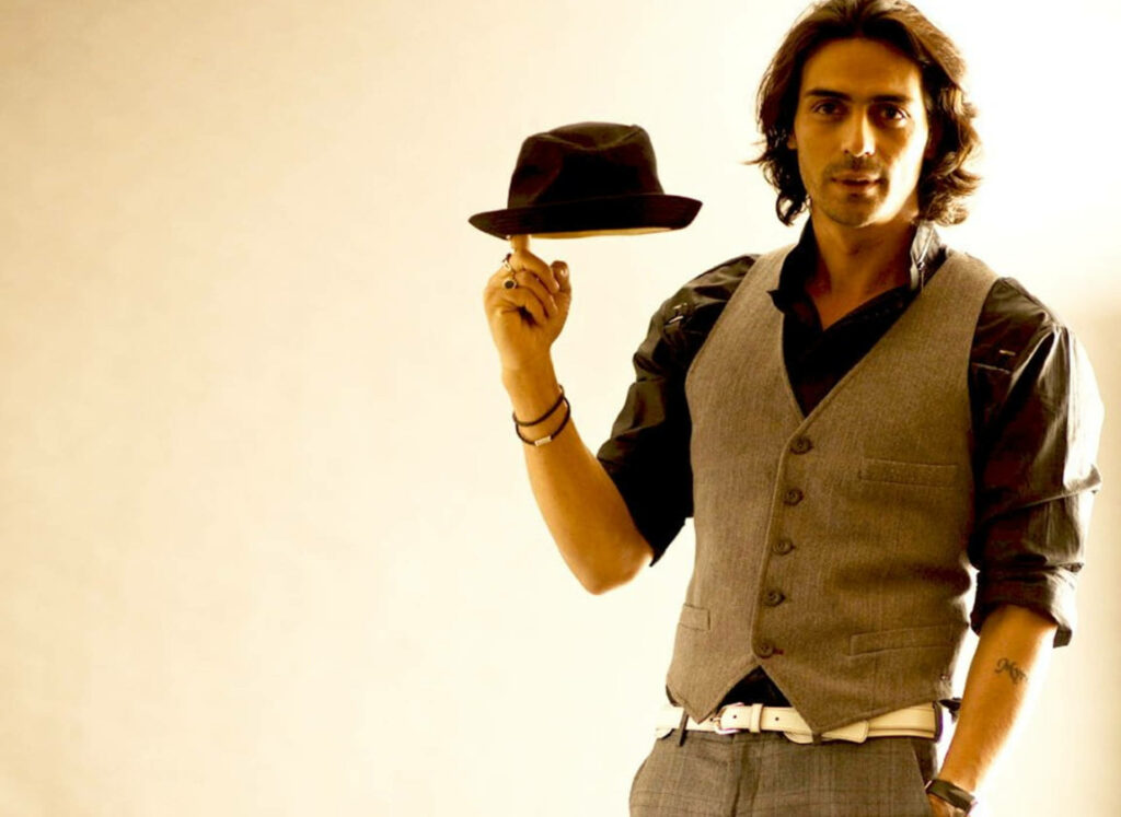 Arjun Rampal stylishly spins fedora hat wearing vest and shirt warm softly lit background wallpaper