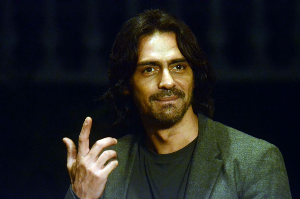 Arjun Rampal in stylish gray suit with confident relaxed expression striking wallpaper background