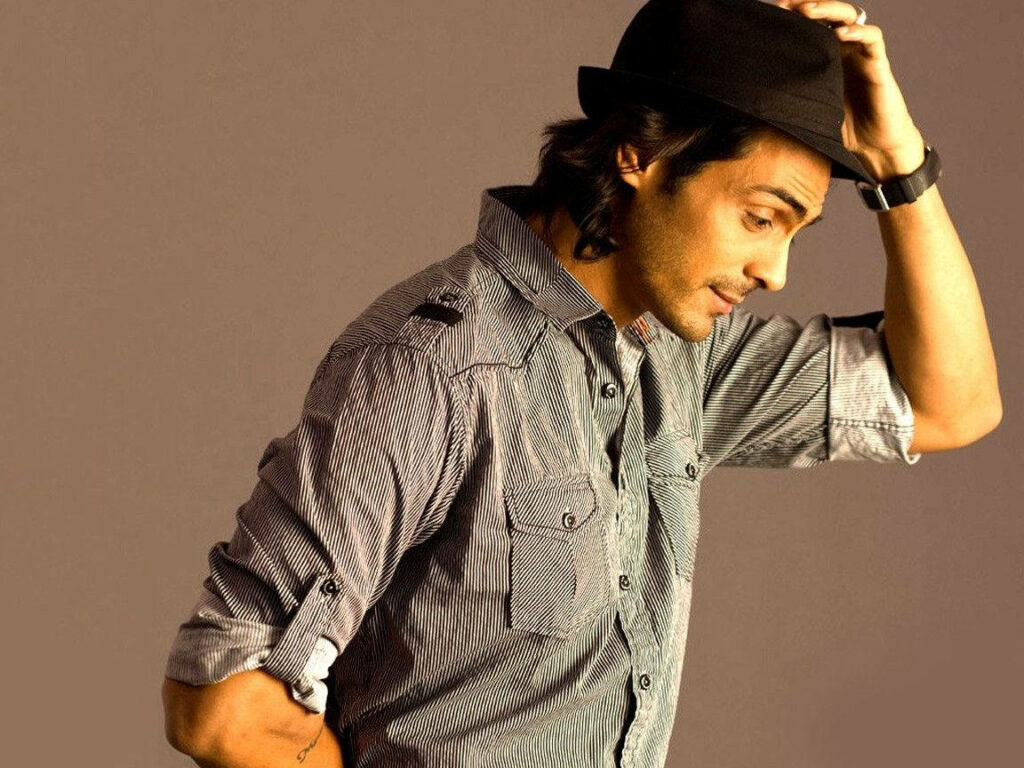 Arjun Rampal posing stylishly in striped shirt and fedora hat wallpaper background charm