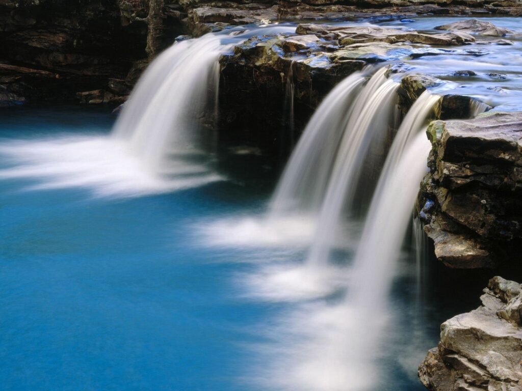 Serene Arkansas waterfall cascading over rugged stones into vibrant blue pool nature wallpaper