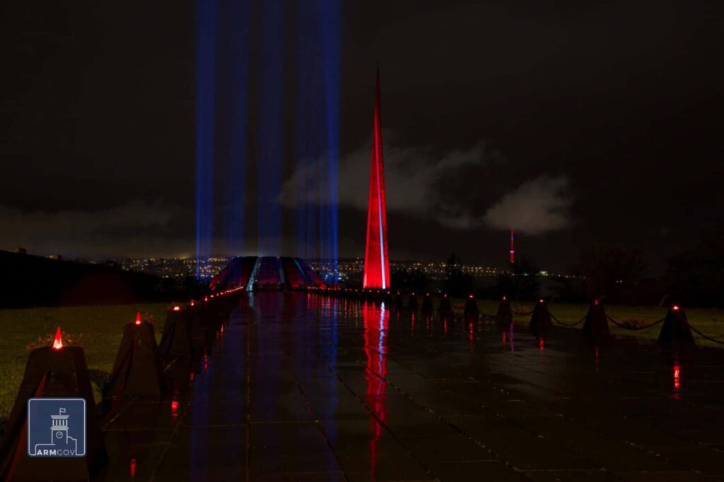 Armenian Genocide Memorial Tsitsernakaberd at night lit with blue and red lights reflecting on path Wallpaper