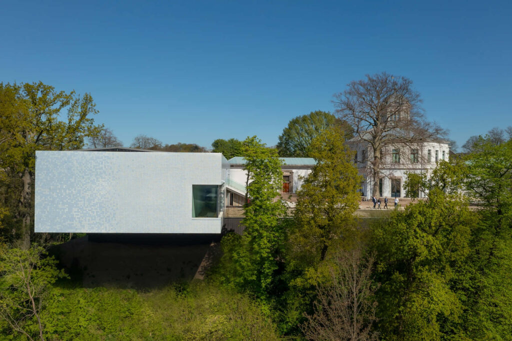 Modern and classic architecture in Arnhem with sleek building and historic mansion under blue sky Wallpaper