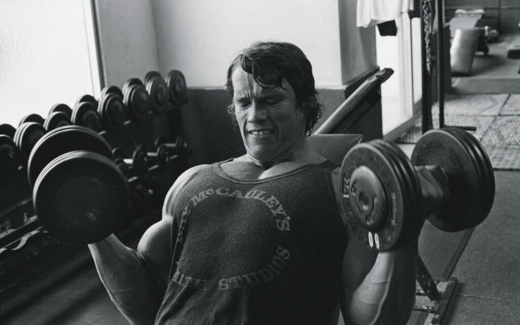 Arnold Schwarzenegger Intense Gym Workout Wallpaper Background