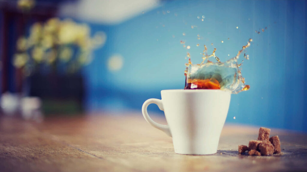 Aromatic tea splash in ceramic cup on rustic table with soft flowers and cozy blue background Wallpaper