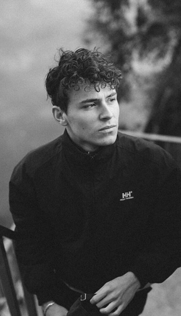 Arón Piper monochrome portrait with curly hair thoughtful pose blurred outdoor background wallpaper