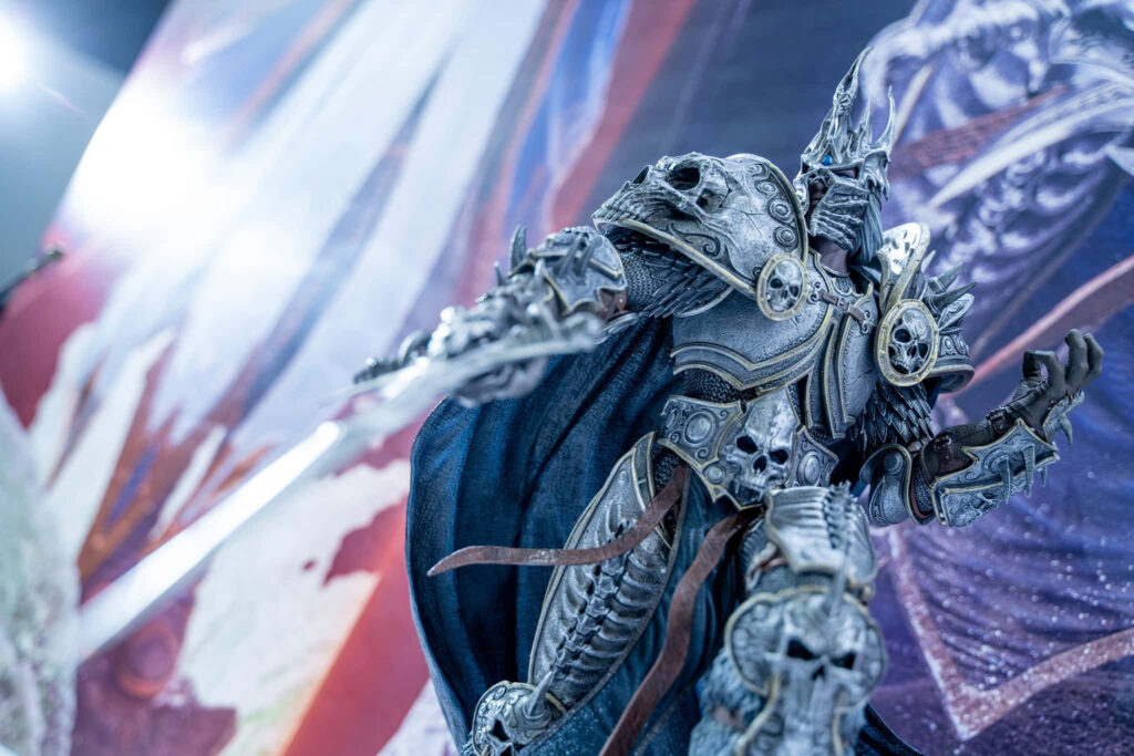 Arthas Menethil cosplay figure in detailed armor wielding sword against vibrant fantasy wallpaper background