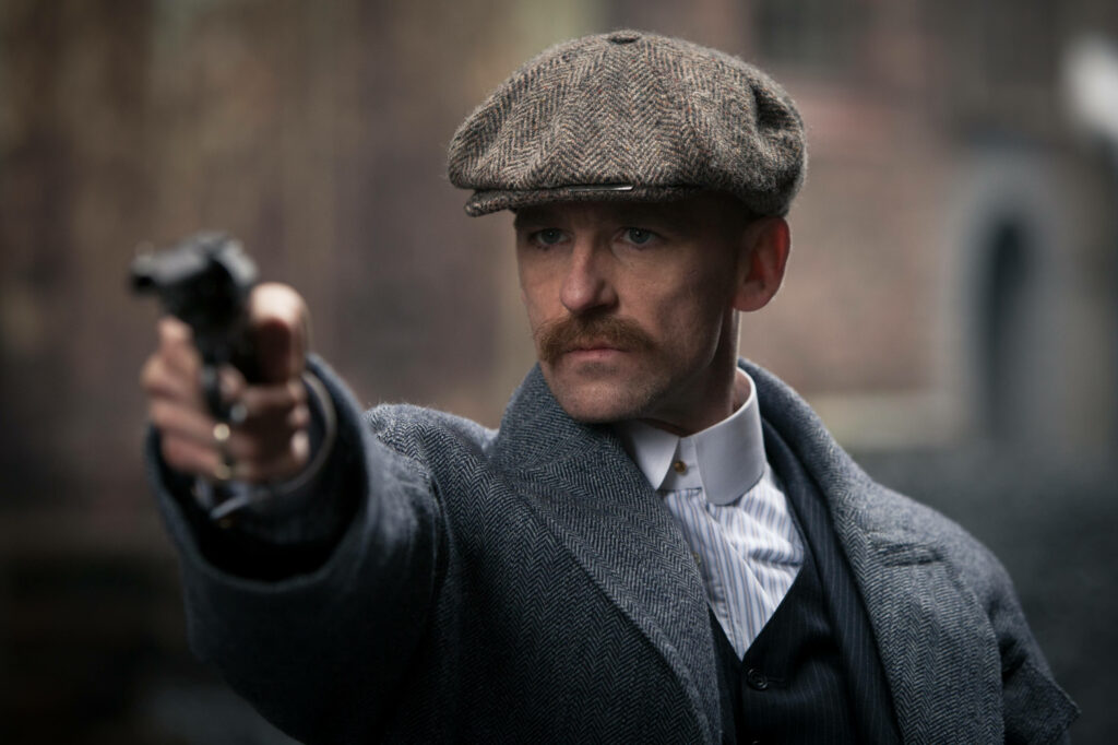 Gangster Chic: Arthur Shelby's Gun-toting Swagger in 8k Ultra HD Wallpaper - Stylish Peaky Blinders Background Image