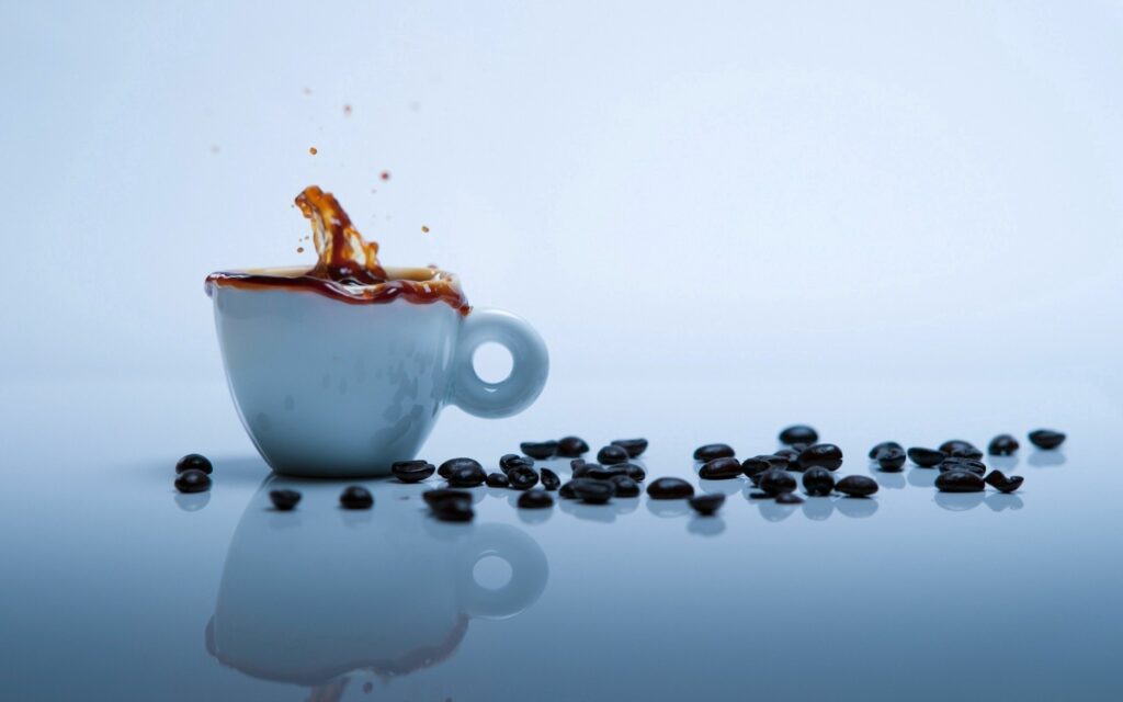 Artistic Coffee Splash: White Cup & Beans on Reflective Wallpaper