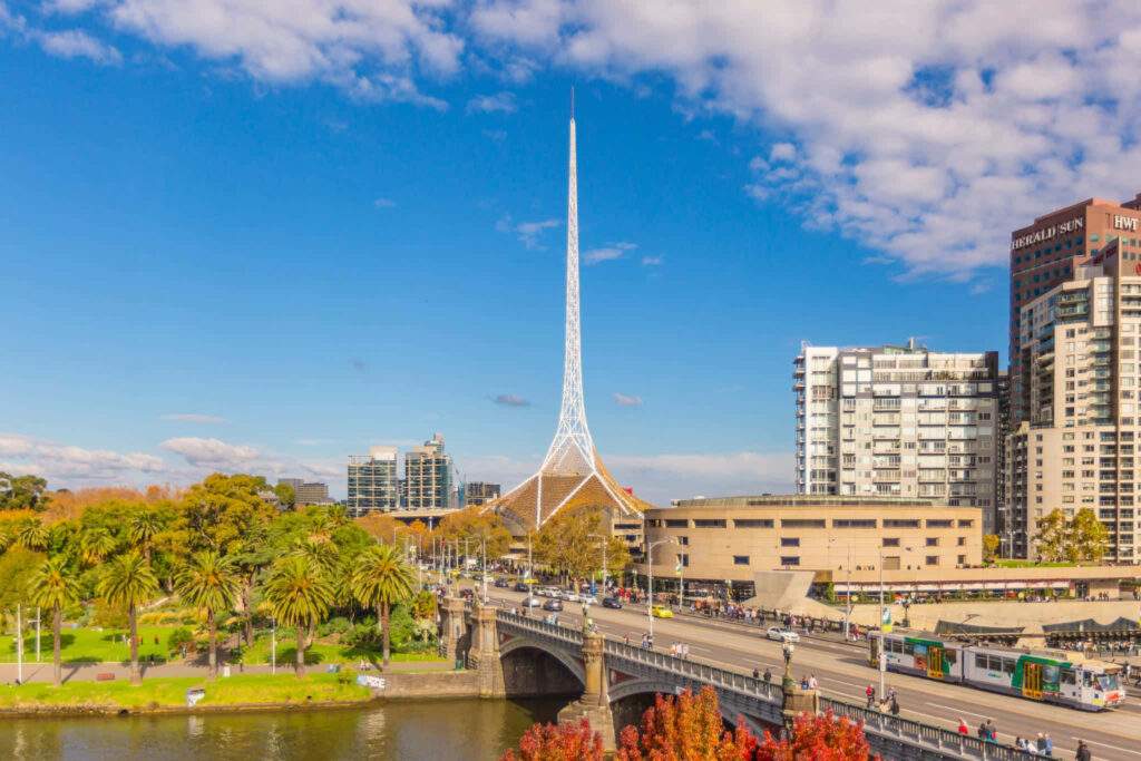Arts Centre Melbourne Spire city skyline with riverside greenery busy streets clear blue sky Wallpaper