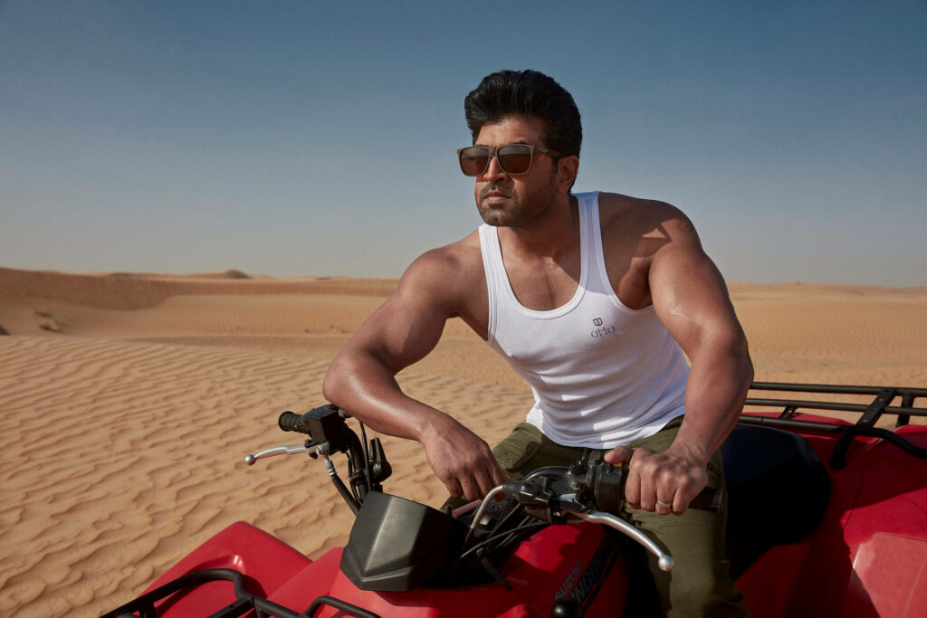 Arun Vijay riding ATV across golden desert sands under bright sun dynamic wallpaper background