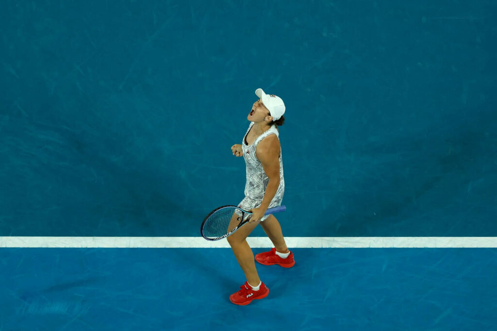 Ashleigh Barty celebrates passionately on vibrant blue tennis court displaying intense spirit Wallpaper
