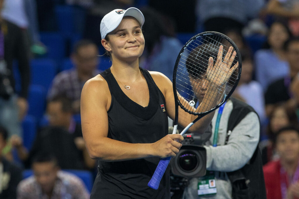 Ashleigh Barty smiling on tennis court holding black racket wearing black outfit and white cap Wallpaper