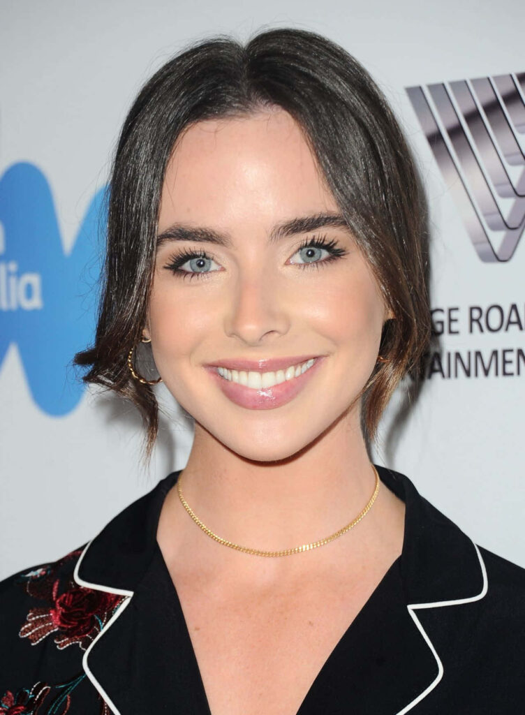 Ashleigh Brewer smiles wearing a stylish black embroidered outfit at branded event backdrop Wallpaper