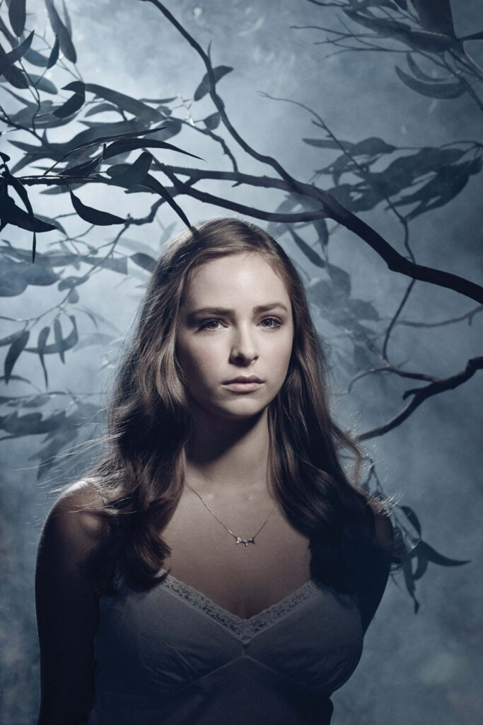 Ashleigh Cummings stands under twisting tree branches with soft moody lighting wallpaper background