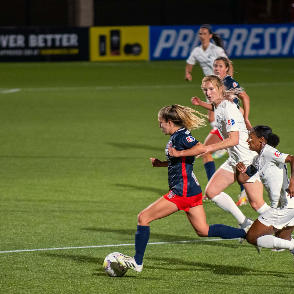 Ashley Sanchez sprinting with soccer ball in intense competitive match action wallpaper background