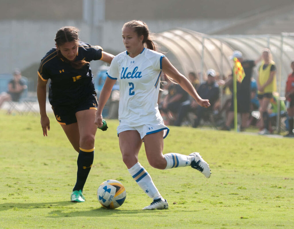 Ashley Sanchez controlling soccer ball during intense match action on vibrant wallpaper background