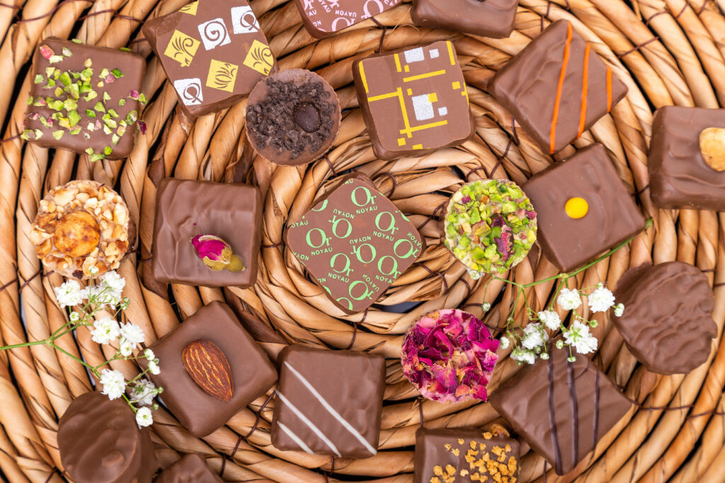 Assorted chocolates with nuts dried flowers on woven wicker background with white blossoms wallpaper