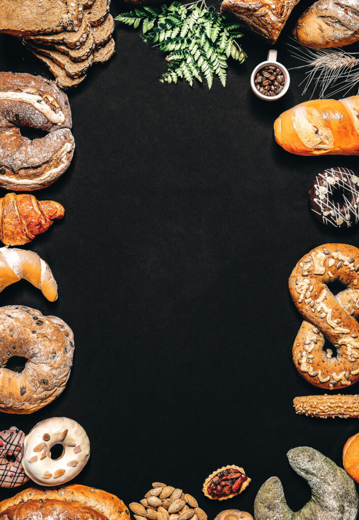Assorted pastry border with croissants pretzels baguettes and donuts on black background wallpaper