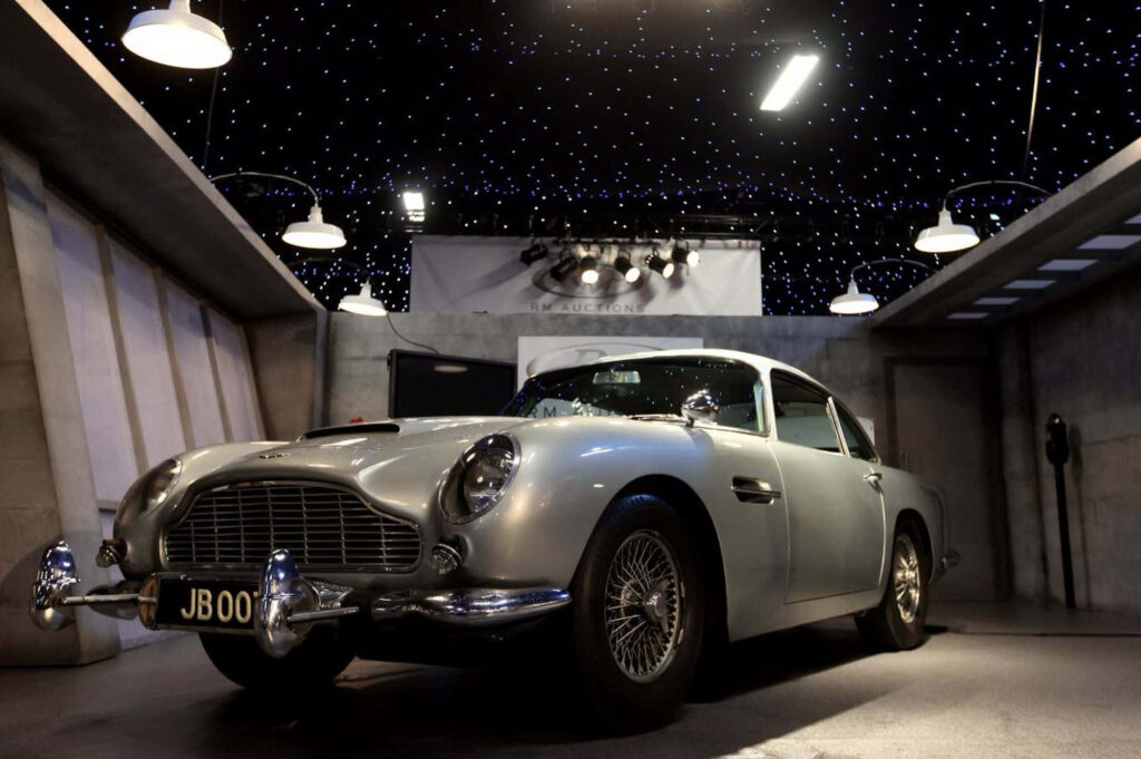 Aston Martin DB5 classic car wallpaper with dramatic lighting and starry ceiling background