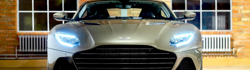 Aston Martin DBS Superleggera front view with signature headlights in front of brick building wallpaper