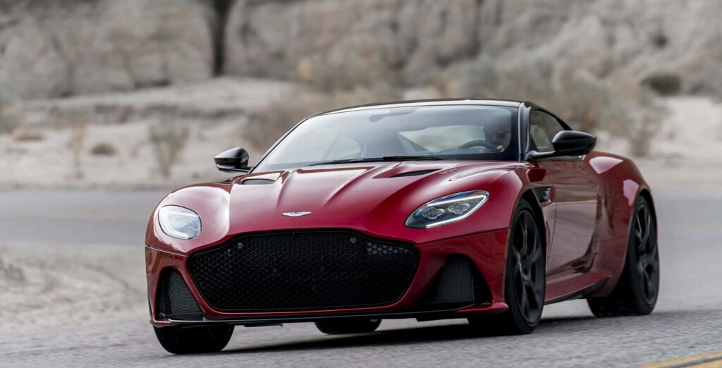 Aston Martin DBS Superleggera red sports car against rugged natural landscape wallpaper background