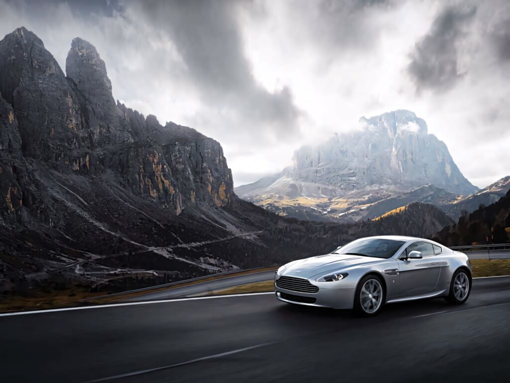 Aston Martin V12 Vantage racing on winding mountain road showcasing power and scenic beauty Wallpaper