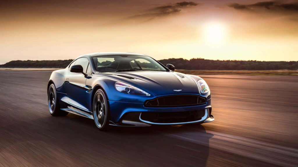 Aston Martin V12 Vantage speeding on open road at sunset showcasing sleek design and power Wallpaper