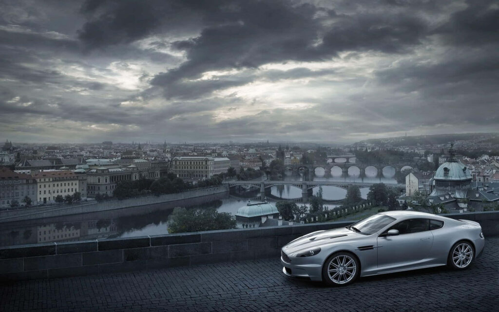 Aston Martin V12 Vantage sleek sports car with dramatic cityscape and moody sky background Wallpaper