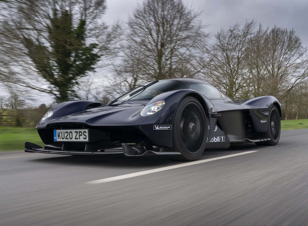 Aston Martin Valkyrie hypercar in motion on open road luxury performance wallpaper background