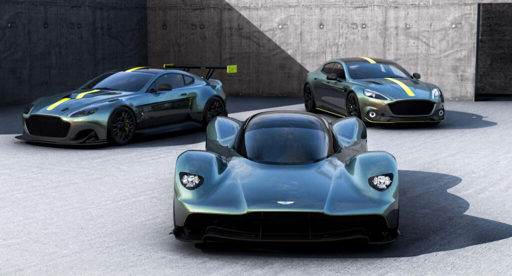 Aston Martin Valkyrie and two models on minimalist concrete backdrop showcasing sleek design Wallpaper