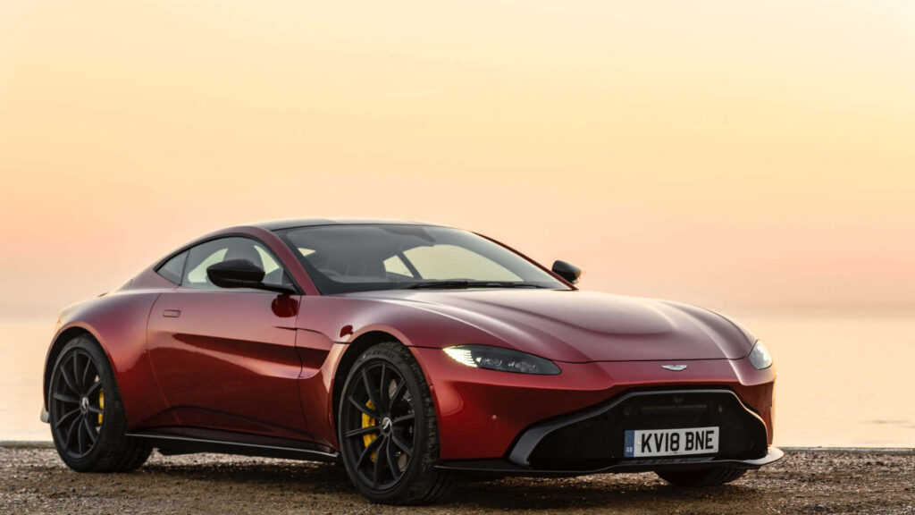 Aston Martin Vantage metallic red luxury sports car at sunset with serene wallpaper background