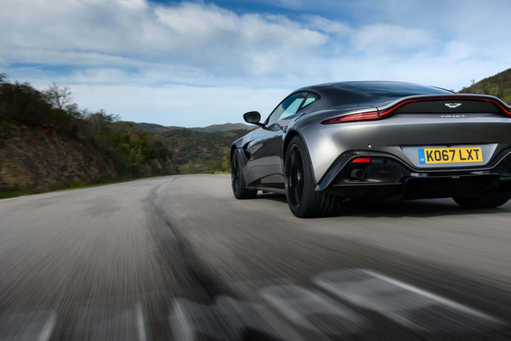 Aston Martin Vantage speeding on open road luxury sports car high performance scenic wallpaper