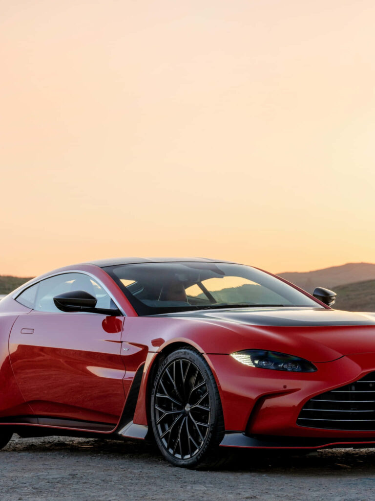 Aston Martin Vantage at sunset showcasing sleek curves in a scenic landscape wallpaper background