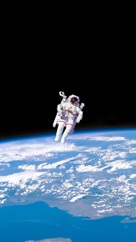 Astronaut Bruce McCandless II untethered spacewalk over Earth vibrant blue clouds NASA photo Wallpaper