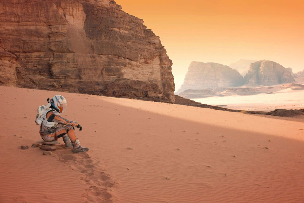 Astronaut on Mars red sands with towering rocky cliffs and rugged landscape wallpaper background