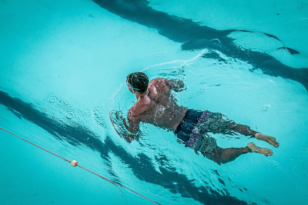 Athletic man swimming in vibrant turquoise pool with clear lane markings in motion Wallpaper