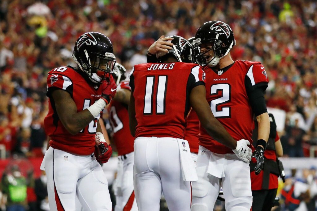 Atlanta Falcons players celebrate with head bump showing team unity during intense football game Wallpaper