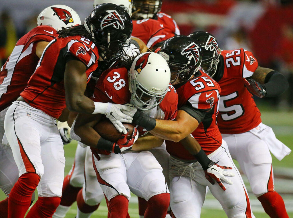 Atlanta Falcons players in red uniforms tackle Arizona Cardinals player during intense football game Wallpaper